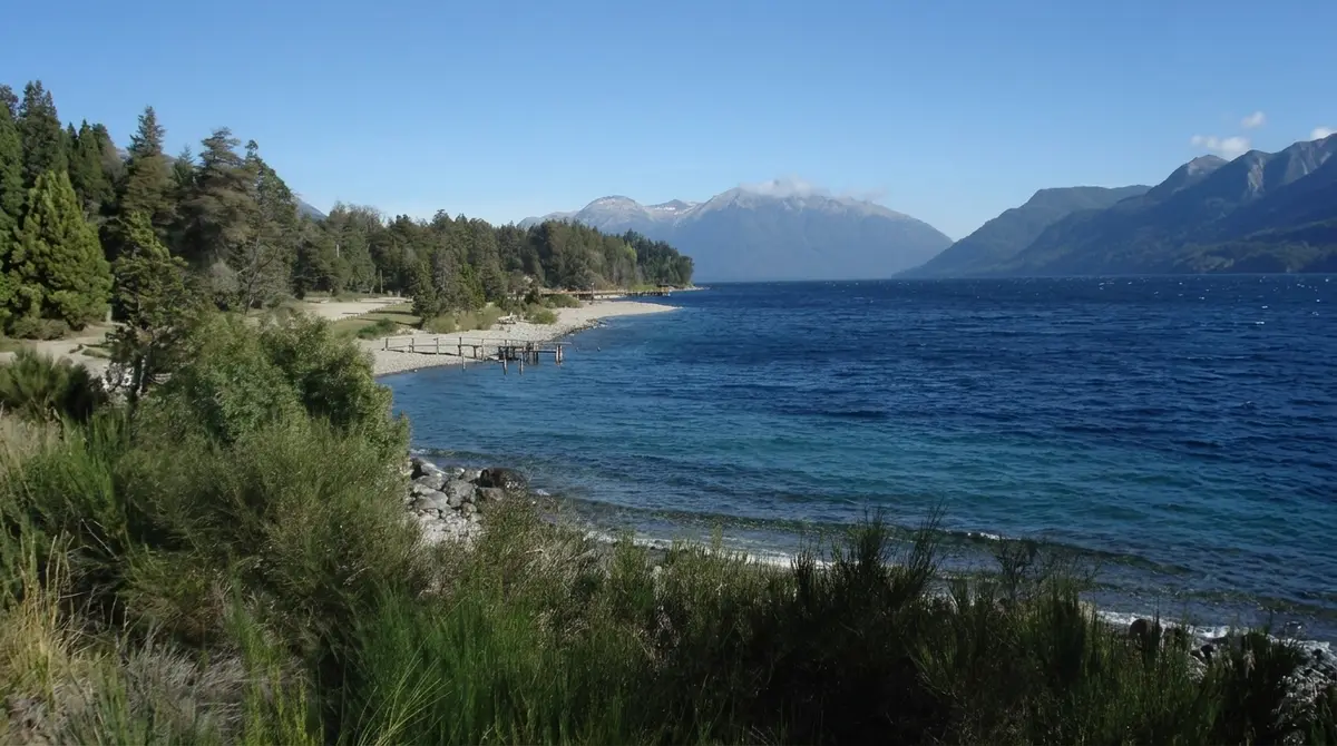 Playa y muelle de Villa Traful sobre el lago, con la cordillera nevada al fondo Playa y muelle de Villa Traful sobre el lago, con la cordillera nevada al fondo